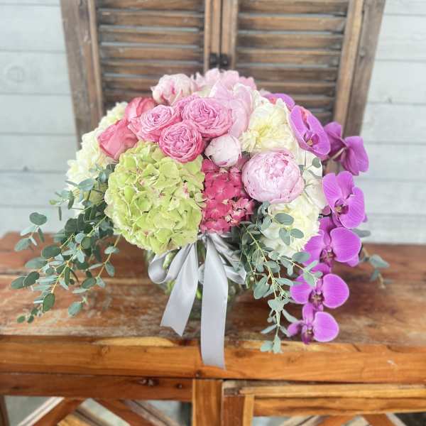 Pink and white floral arrangement with orchids and hydrangeas in a vase