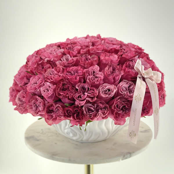 Large dome of pink roses in a white vase with a ribbon bow