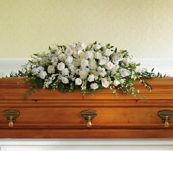 White floral spray arranged on a wooden casket