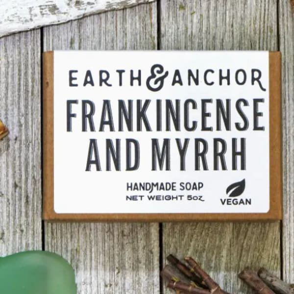 Frankincense and myrrh handmade soap bar on rustic wood with herbal accents