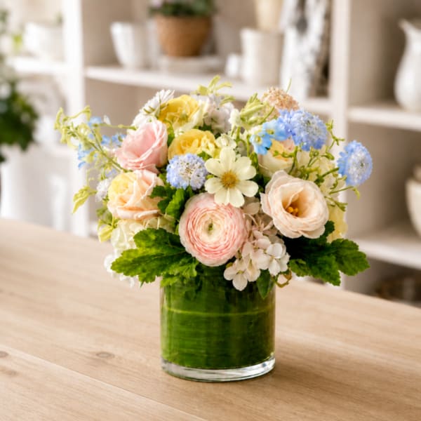 Mixed pastel flowers in a clear glass vase on a table