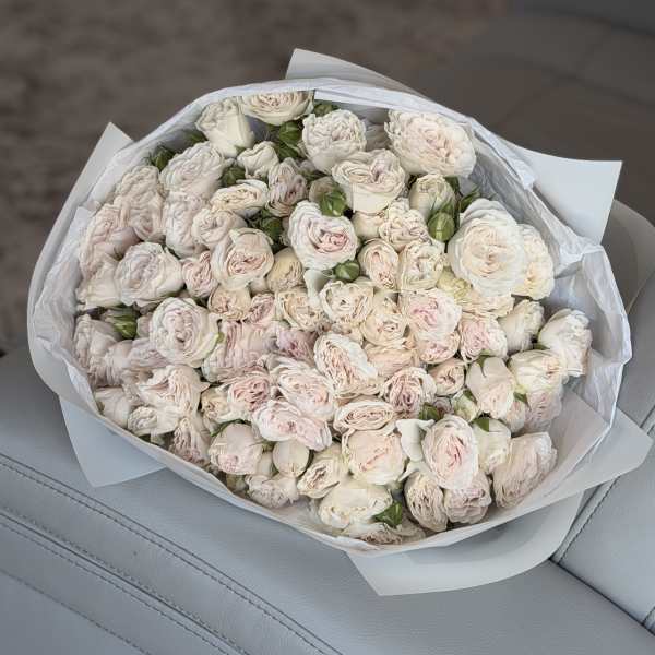 Bouquet of pale pink and white roses wrapped in white paper