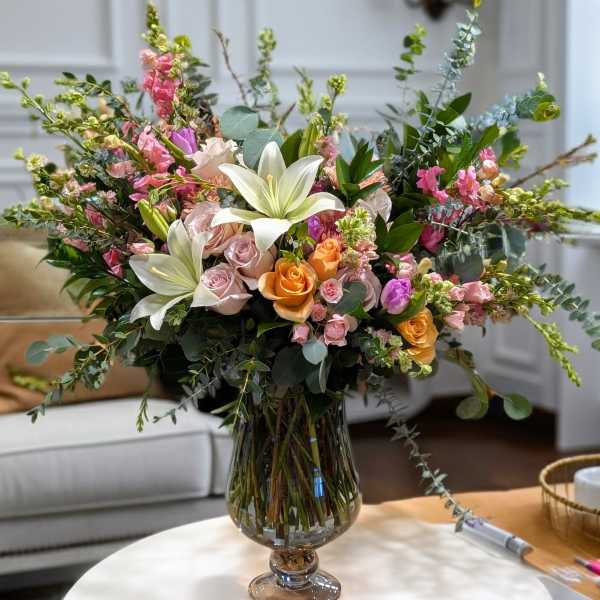 Mixed bouquet of lilies, roses, and pink blooms in a glass vase