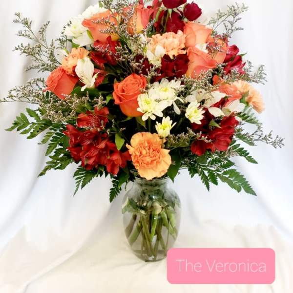 Mixed bouquet of red, peach, and white flowers in a glass vase