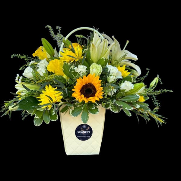Yellow and white mixed flower arrangement in a cream container