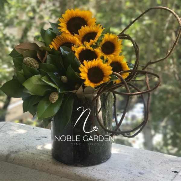 Sunflower arrangement in a dark vase with looping branches