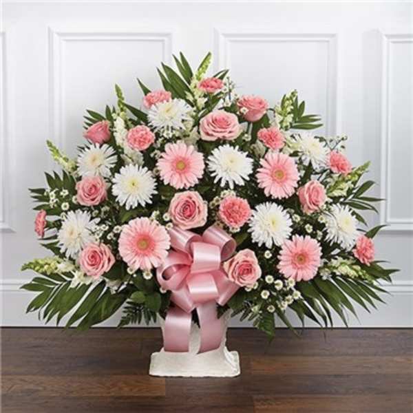 Pink and white floral arrangement in a white vase with a pink ribbon