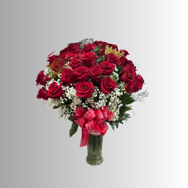 Bouquet of red roses with baby's breath in a glass vase and pink ribbon