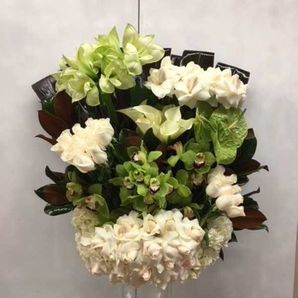 Tall arrangement of green and white orchids in a clear glass vase