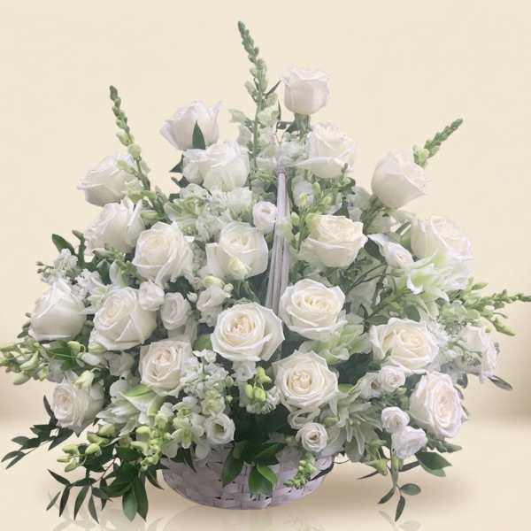 White rose arrangement in a low white basket