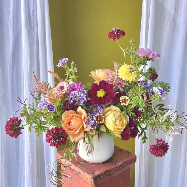 Mixed bouquet in a white vase with pink, yellow, and purple flowers