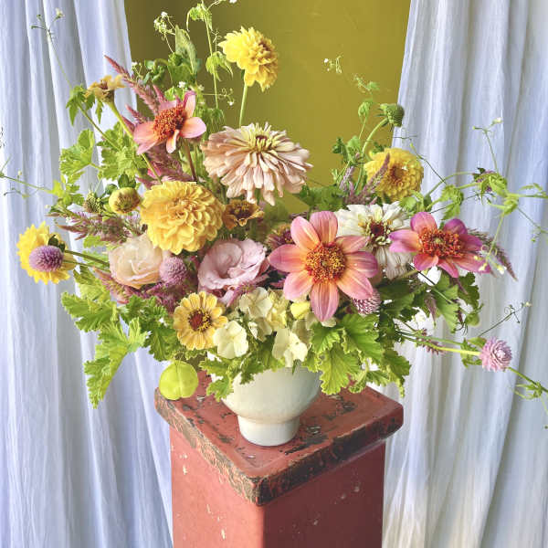 Mixed bouquet of pink, yellow, and white flowers in a white vase