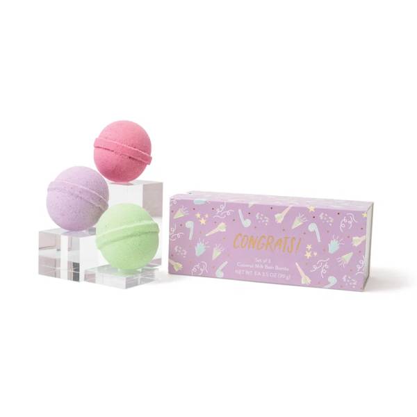 Three pastel bath bombs beside a purple gift box