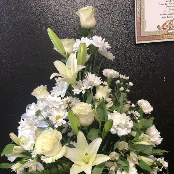 White lilies and roses arranged in a wicker basket with white daisies