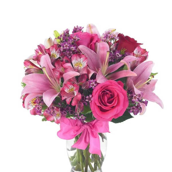 Pink and purple bouquet in a clear glass vase with a pink ribbon