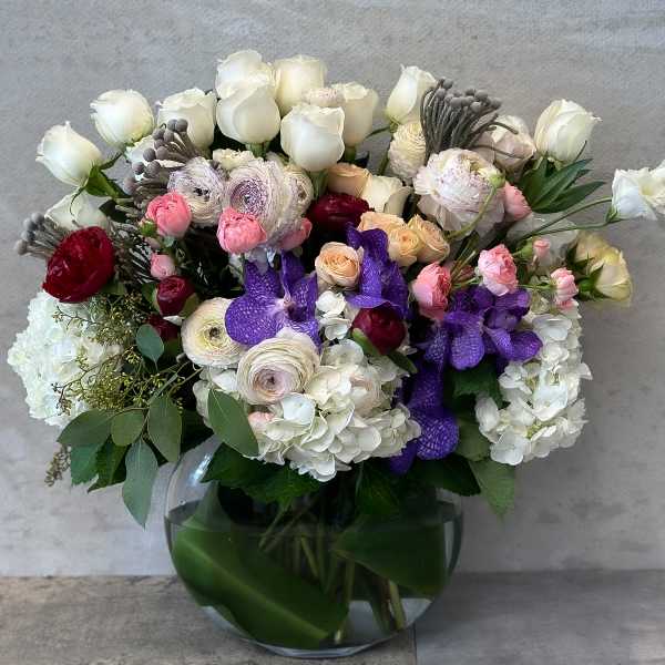 Mixed bouquet of white, pink, purple, and red flowers in a glass vase