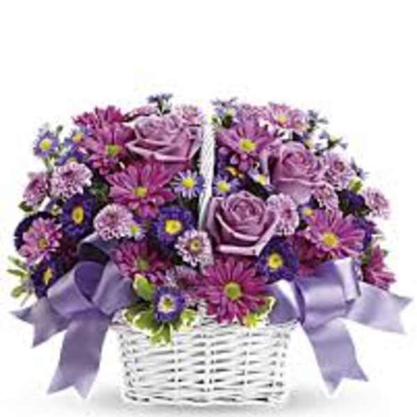 Purple flower arrangement in a white wicker basket with lavender ribbons