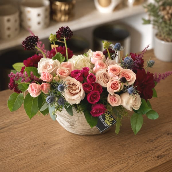 Mixed pink and cream roses in a low ceramic bowl