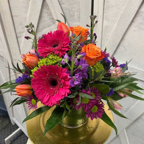 Bright mixed bouquet in a glass vase with pink gerberas and orange roses