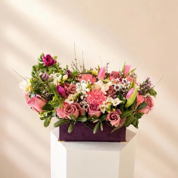 Pink and white mixed flower arrangement in a purple box