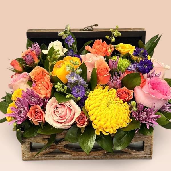 Mixed bouquet in a wooden box with pink, yellow, purple, and coral blooms