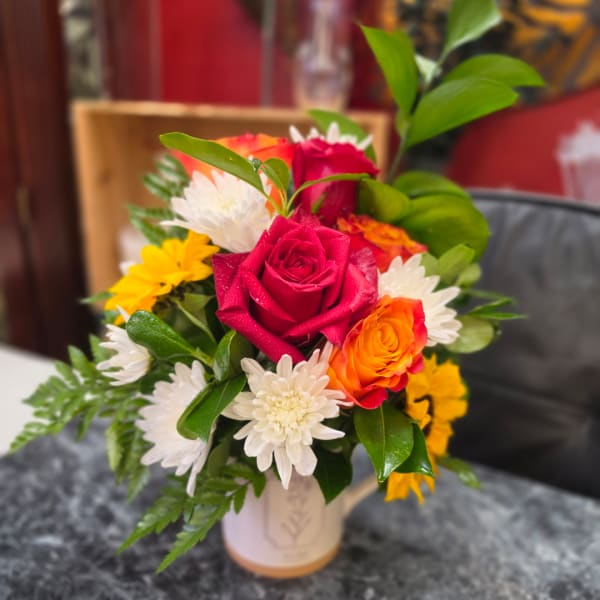 Mixed bouquet of roses and white daisies in a small vase
