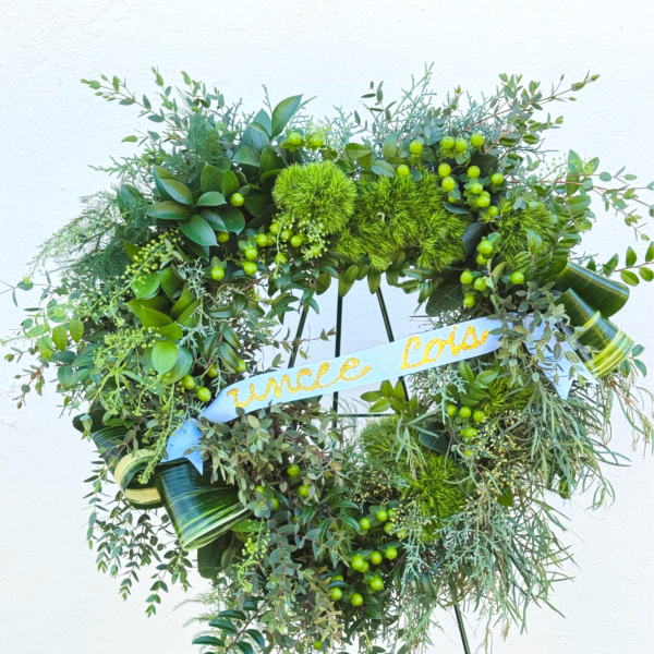 Heart-shaped green wreath on an easel with a blue ribbon