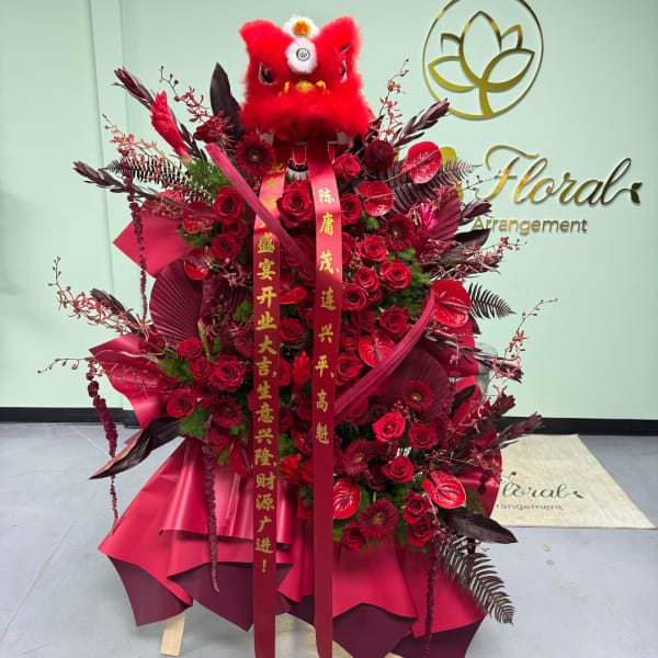 Large red floral arrangement with roses and ribbons, topped by a red lion head decoration