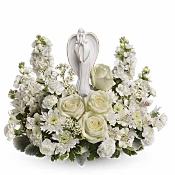 White floral arrangement with roses and a praying angel figurine