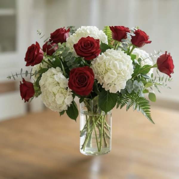 Red roses and white hydrangeas in a clear glass vase