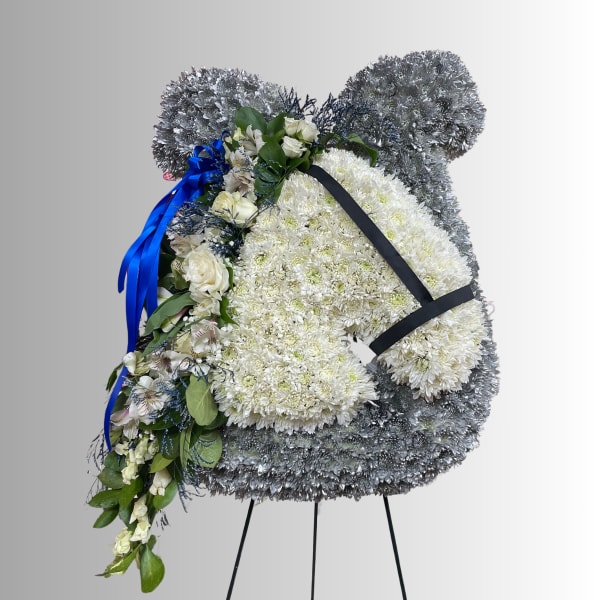 Large white and silver floral standing spray on an easel with blue ribbon