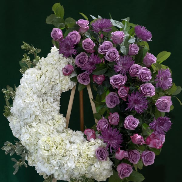 Floral wreath with white hydrangeas, purple roses, and purple mums on an easel