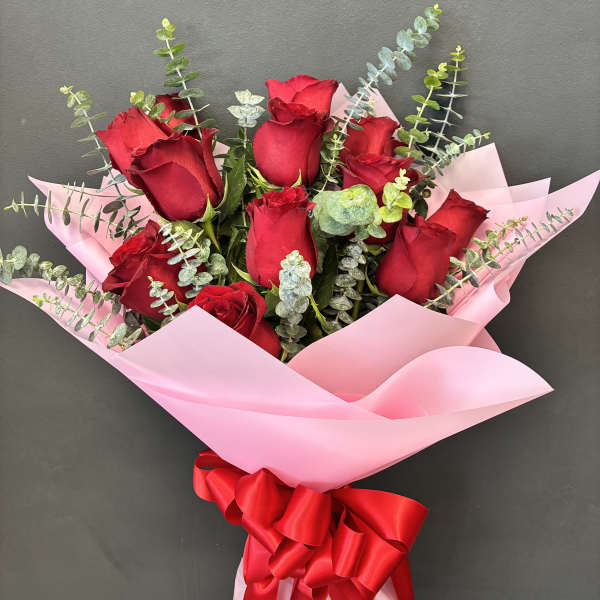 Bouquet of red roses wrapped in pink paper with a red ribbon