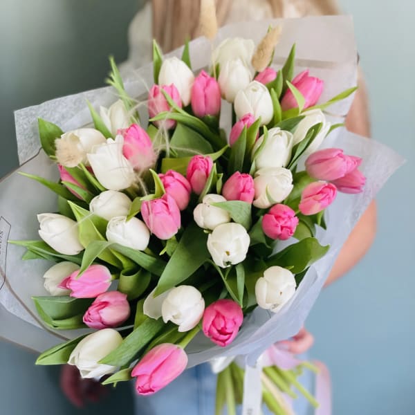 Hand-tied bouquet of pink and white tulips wrapped in white paper