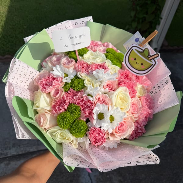 Bouquet of pink and white roses, carnations, and daisies with a small sign