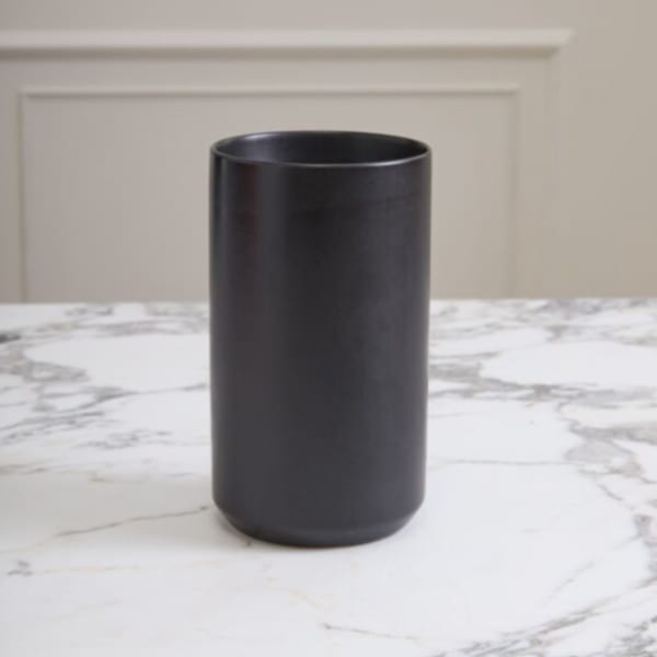 Black cylindrical vase on a marble surface