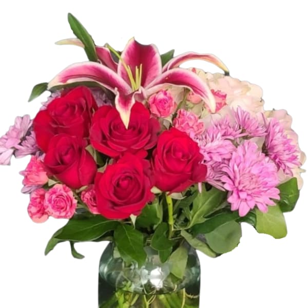 Bouquet of red roses, pink lilies, and lavender daisies in a glass vase