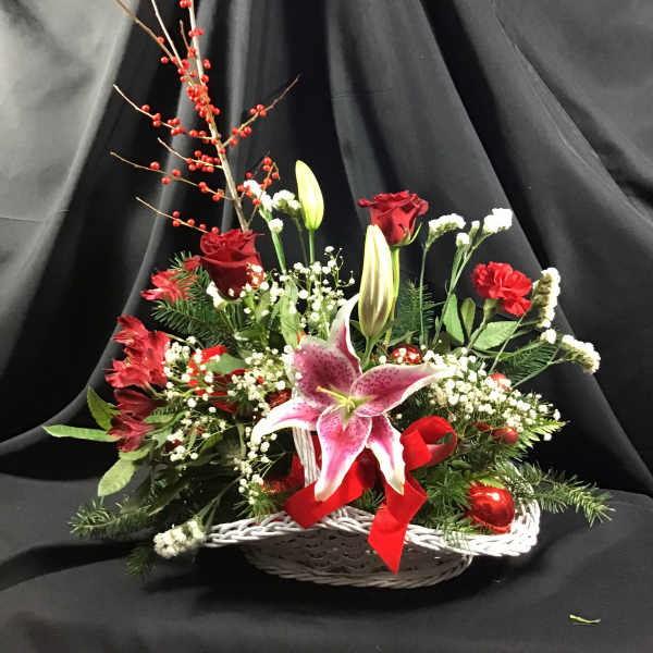 Basket arrangement with pink lilies, red roses, and red berries