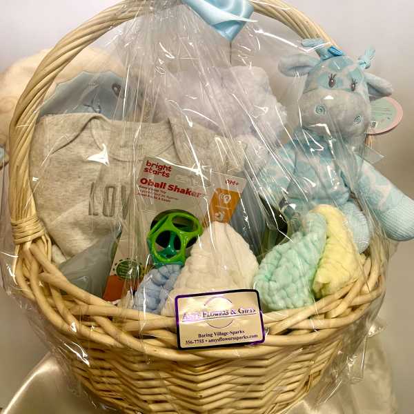 Gift basket with baby clothes, plush toys, and a teether