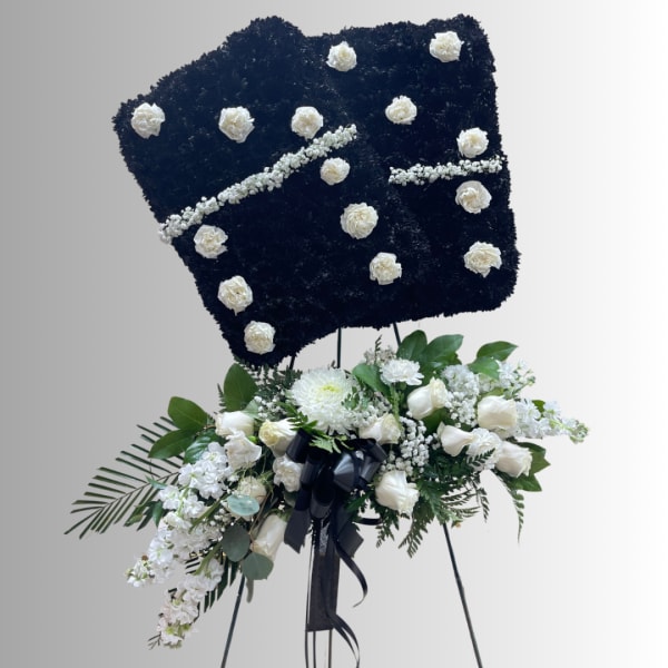 White floral standing spray on an easel with a black floral tribute board above it