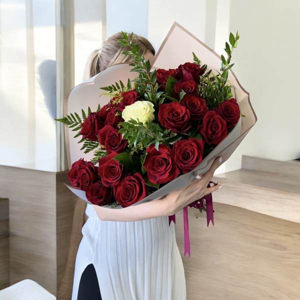 Bouquet of red roses with one white rose in pale wrapping