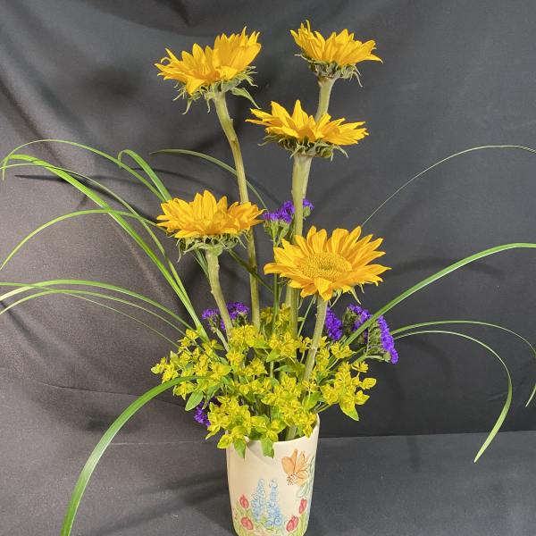 Yellow sunflowers in a decorated ceramic vase with purple filler flowers