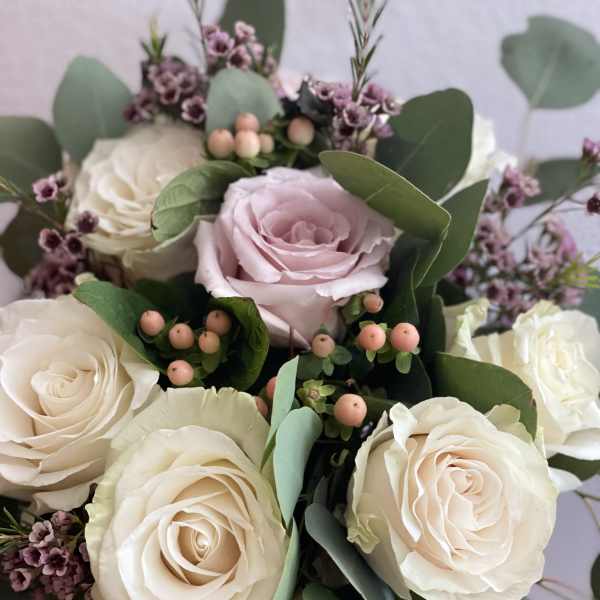 Bouquet of cream and blush roses with eucalyptus and small purple filler flowers