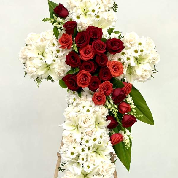 Standing floral cross with red and white roses and lilies on an easel