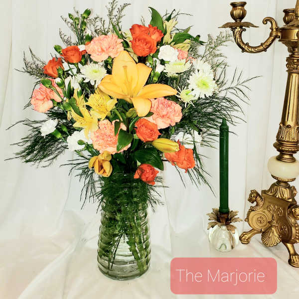 Mixed bouquet of orange, yellow, pink, and white flowers in a glass vase