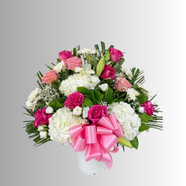 Pink and white flower arrangement in a white vase with a pink bow