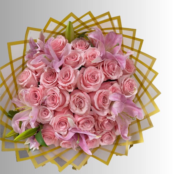 Pink roses and lilies arranged in a round bouquet with gold geometric wrap