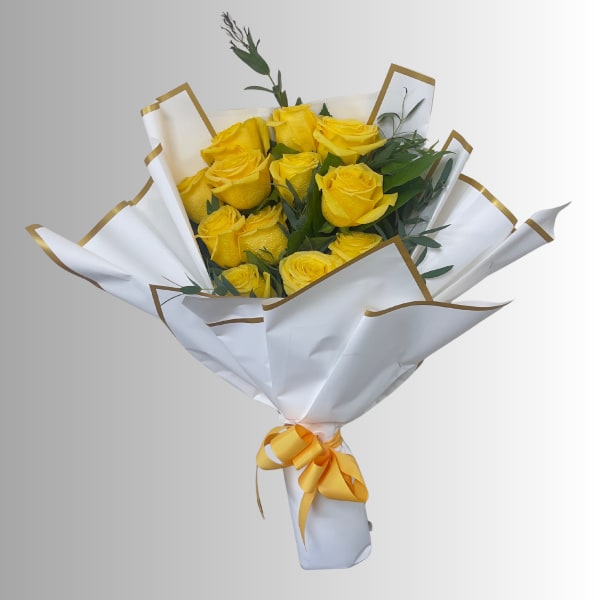 Bouquet of yellow roses wrapped in white paper with gold trim and a yellow ribbon