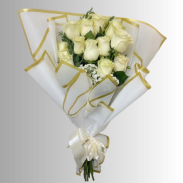 Bouquet of cream roses wrapped in white paper with gold trim and a ribbon