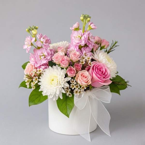 Pink and white flower arrangement in a white box with a sheer ribbon